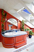 Custom bathtub installation with curved wooden surround painted red below skylights