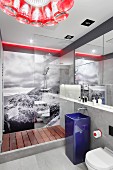 Designer bathroom with blue pedestal sink in front of glazed shower area with black and white photo mural