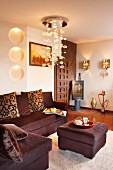 Pendant lamp with glass bubbles above dark brown corner sofa with matching ottoman; elegant interior with ethnic elements