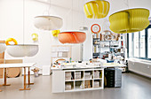 Pendant lamps with huge colourful slatted lampshades above desks in workshop