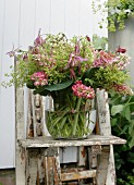 Glass vase of pink lupins on weathered wooden chair