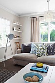 Grey sofa with scatter cushions & tripod, studio-style standard lamp in modern living room