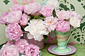 Pink and white peonies in a retro vase in front of a wall painted with a stencil design