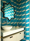 Modern washstand with countertop basin below star-shaped mirror on tiled wall with blue and white 3D pattern