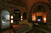 Lamps in living area with couch and work area in niche in old house with vaulted ceiling and limestone walls