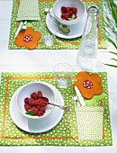 A place setting with raspberries and a homemade placemat with a floral pattern