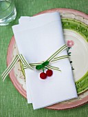 Linen napkin with ribbon and crocheted cherries on ceramic plate