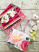 Colourful towels, eye mask with butterfly pattern, soaps and toothbrushes arranged on vintage wooden surface