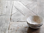 Three hand-crafted grey bowls on wooden surface