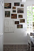 Gallery of floral paintings on wall next to window in rustic dining room