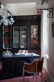 Rococo armchair, desk and fitted, dark-wood cabinets with glass doors in study