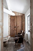 Blick durch offene Tür auf antike Sessel im Rokoko Stil, im Hintergrund rustikale Holztür