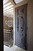 Carved door next to balustrade with view of traditional chandelier in background