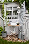 Vintage Waschschüssel und Krug in rostigem Metallgestell vor Gartenhäuschen