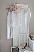 Nostalgische Kleider in Weiß an weiss lackiertem Holzpaneel vor pastellfarbener Wand