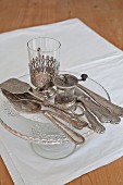 Vintage silver cutlery on cake stand and white place mat