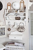 Shelves of decorative plates and salt cellars above white-painted console cabinet against pastel wall