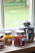 Labelled jars and tin of spices on windowsill