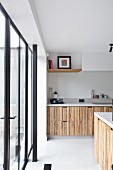 Moderne Küche mit Holzfront, seitlich Terrassentür mit schwarzem Metallrahmen