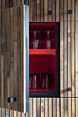 Offene Küchenschranktür mit Holzfront, innenseitig rotlackiert, auf Ablage Gläser