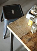 Teilweise sichtbare Kiste mit Gewürzgläsern auf Holztisch, dahinter Retro Metallhocker