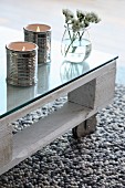 Ceramic tealight holders shaped like tin cans on coffee table made from white-painted wooden pallet, glass top and castors