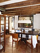 Traditional Spanish table and wooden chairs in dining room with wood-beamed ceiling