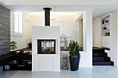 Free-standing, masonry fireplace and planter in front of dining area on platform in modern interior