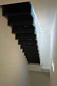 Bottom view of black staircase in narrow, white stairwell
