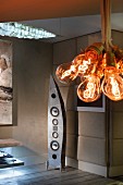 Bundle of light-bulb pendant lamps in front of extravagantly shaped speaker