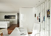 Home office area in open-plan interior with white furnishings, Eames Aluminium Chairs and fitted shelving