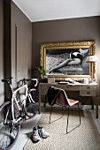 Racing bicycle next to desk below gilt-framed black and white photos