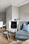 Sofa next to side table and open fireplace in interior painted pale grey