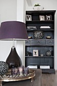 Purple table lamp on coffee table in front of black shelving unit
