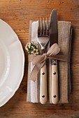 Cutlery and linen napkin tied with ribbon and decorated with waxflowers