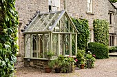 Glass porch in style of Victorian greenhouse over front door of stone house
