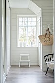 White, wood-panelled hallway with step ladder below window
