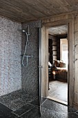 Floor-level shower with mosaic tiles next to open door with view of floor lantern in living area
