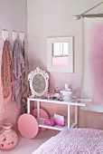 Modern serving trolley with large wheels used as dressing table and painted pink against pink wall