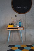 Vintage bottles on console table with legs painted pale blue against exposed concrete wall