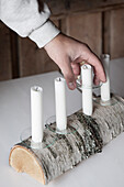 Four white candles in hand-crafted candelabra made from half a birch log and glass drip catchers