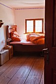 Traditional wooden bed below window in simple farmhouse bedroom