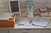 Set of old stamps, small chalkboard and vintage utensils on old table with drawer
