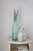 Tulips in old milk bottle and small bottles with vintage-style labels on small, vintage, wall-mounted shelf