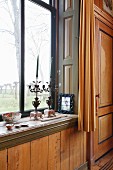 Ornate vintage candlesticks on sill of window with garden view