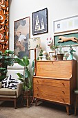 Retro wooden bureau below gallery of pictures and framed carved animal figurine