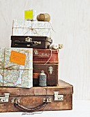 Vintage suitcases of various sizes and packages wrapped in wrapping paper made from old maps