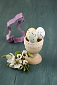 Sugar-coated chocolate eggs in wooden egg cup and pear blossom