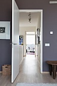 Room with dark grey walls and view through open door down narrow corridor into study