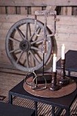 Lit white candles in wooden candlesticks and vintage stirrups on black side table